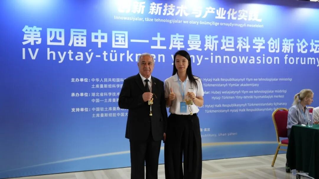阿拉贝尔迪·阿希罗夫院长与内容总监吴晓洁合影，两人手里拿着现场赠送的蕲艾文创
