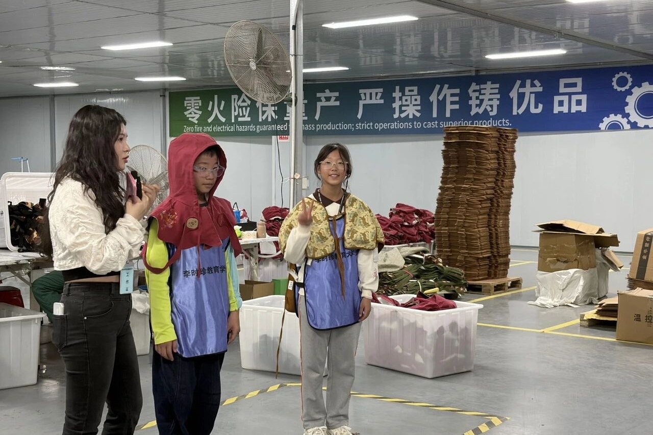 同学们在工作人员帮助下试穿布艺类蕲艾制品